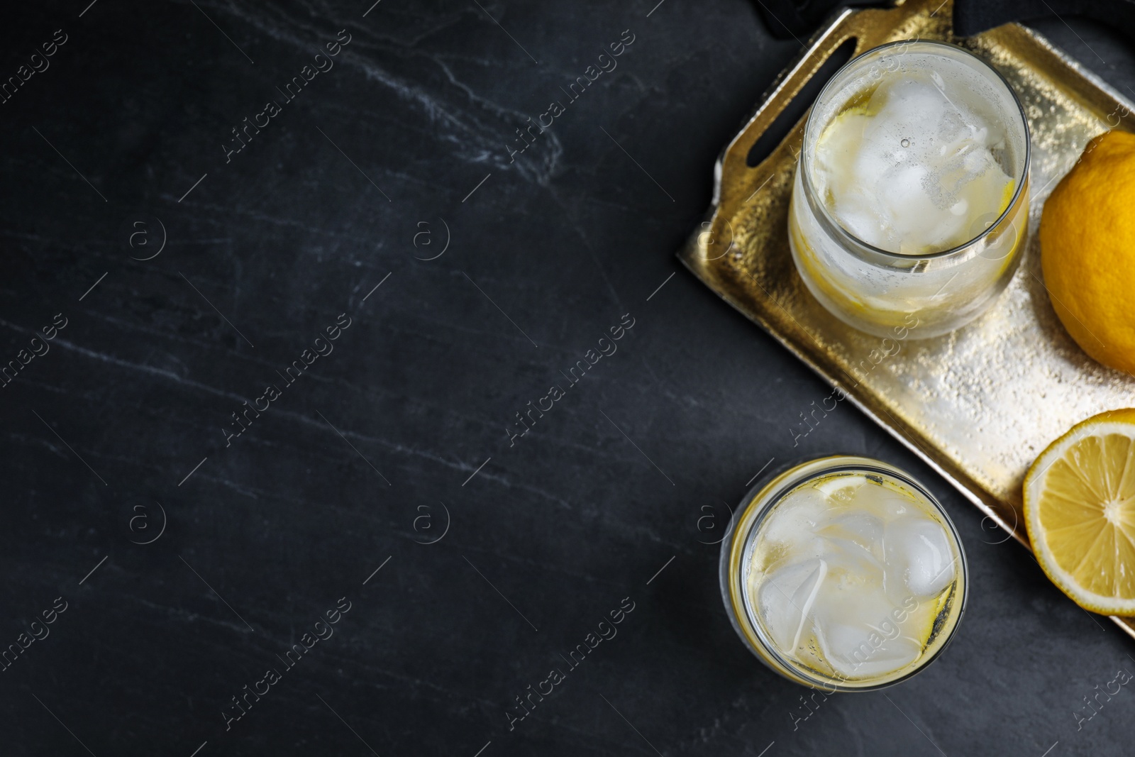 Photo of Soda water with lemon slices and ice cubes on black table, flat lay. Space for text
