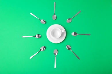 Photo of Flat lay composition of empty cup and new teaspoons on green background