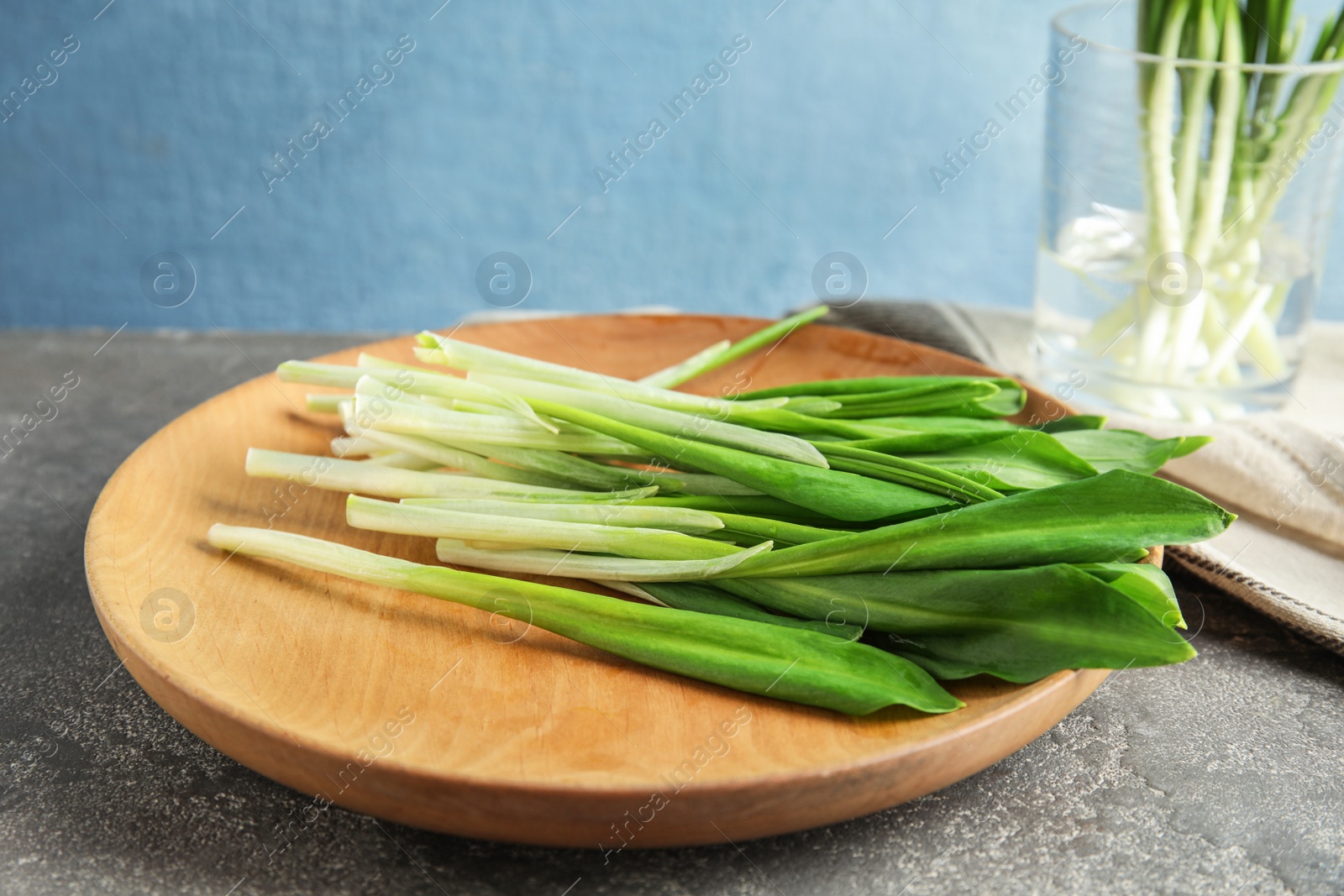 Photo of Plate of wild garlic or ramson on grey table against color background