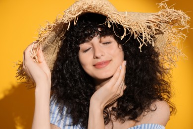 Photo of Beautiful young woman wearing straw hat in sunlight on orange background. Sun protection accessory