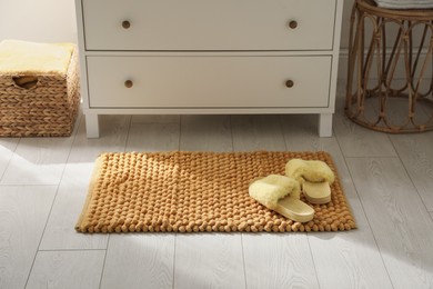 Stylish orange mat with slippers near chest of drawers in bathroom
