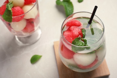 Glass with tasty melon and watermelon ball drink on gray table