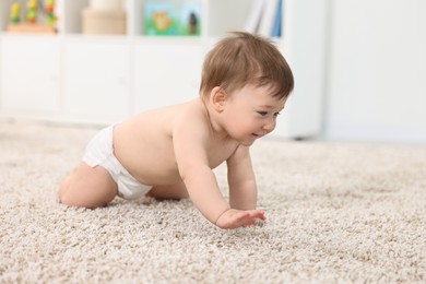 Cute baby boy crawling on carpet at home