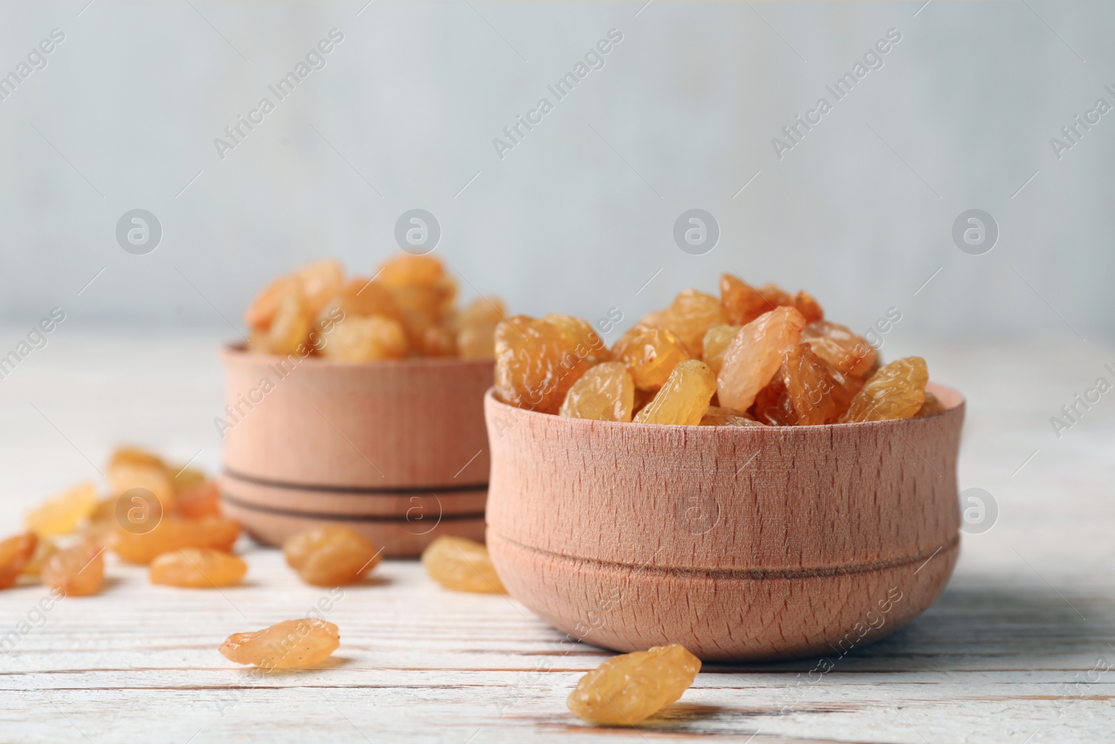 Photo of Bowls with raisins on wooden table, space for text. Dried fruit as healthy snack