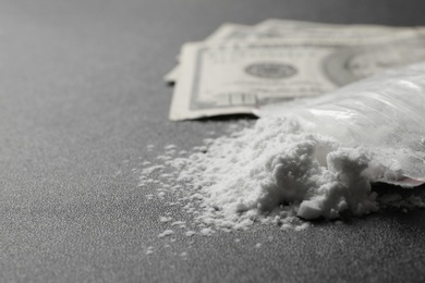 Photo of Cocaine in plastic bag and money on dark background, closeup