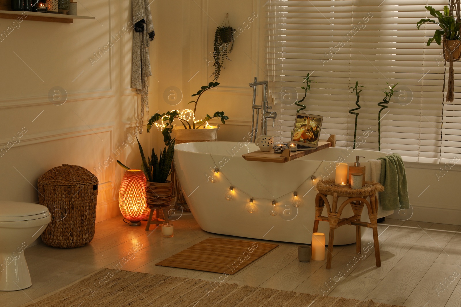 Photo of Stylish bathroom interior with green houseplants and string lights. Idea for design