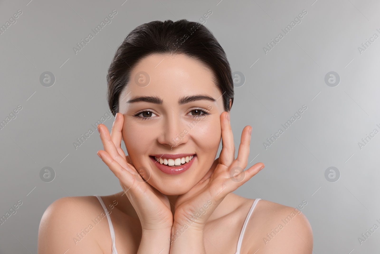 Photo of Young woman massaging her face on grey background