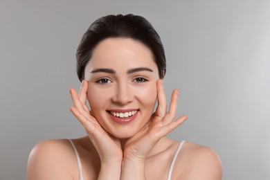 Photo of Young woman massaging her face on grey background