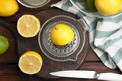 Photo of Glass squeezer and fresh lemons on wooden table, flat lay