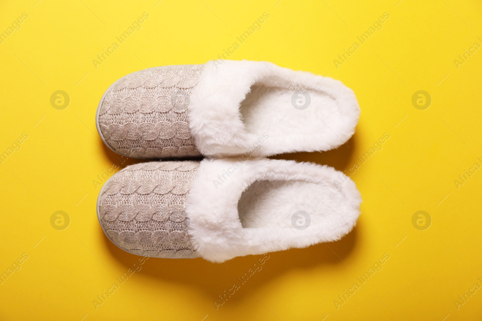 Photo of Pair of beautiful soft slippers on yellow background, top view