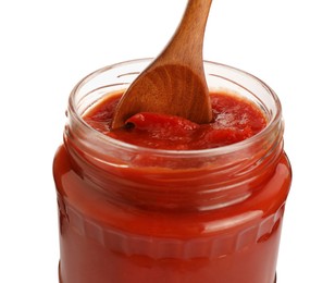 Glass jar of delicious canned lecho with wooden spoon isolated on white, closeup