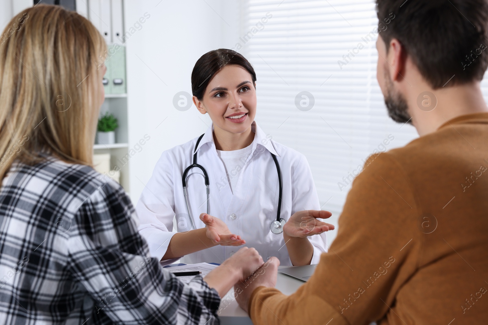 Photo of Couple having appointment with fertility doctor in clinic. Patient consultation