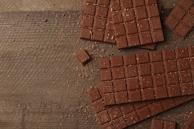 Photo of Tasty chocolate bars on wooden table, flat lay. Space for text