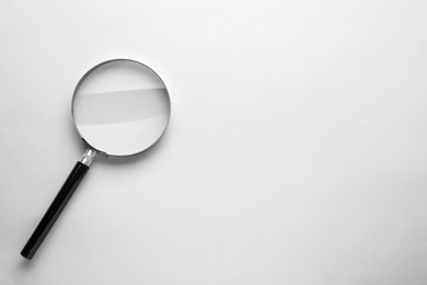 Photo of Magnifying glass on light grey background, top view. Space for text