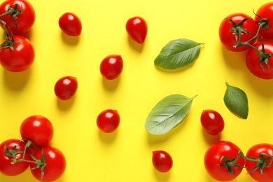 Flat lay composition with ripe cherry tomatoes and basil leaves on color background