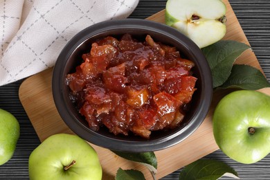 Photo of Bowl of delicious apple jam and fresh fruits on black wooden table, flat lay