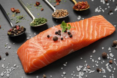 Photo of Fresh salmon and ingredients for marinade on black table, closeup