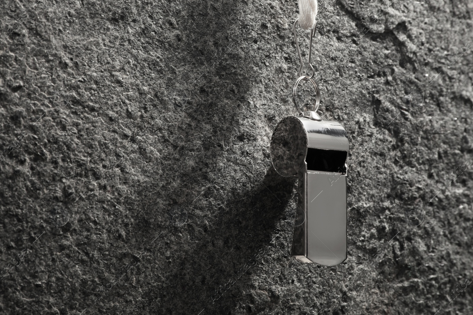 Photo of Referee equipment. Metal whistle on grey textured background, closeup and space for text