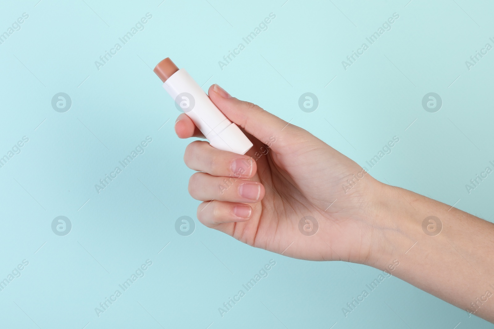 Photo of Woman with lip balm on light turquoise background, closeup