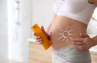 Photo of Young pregnant woman with sun protection cream indoors, closeup. Space for text