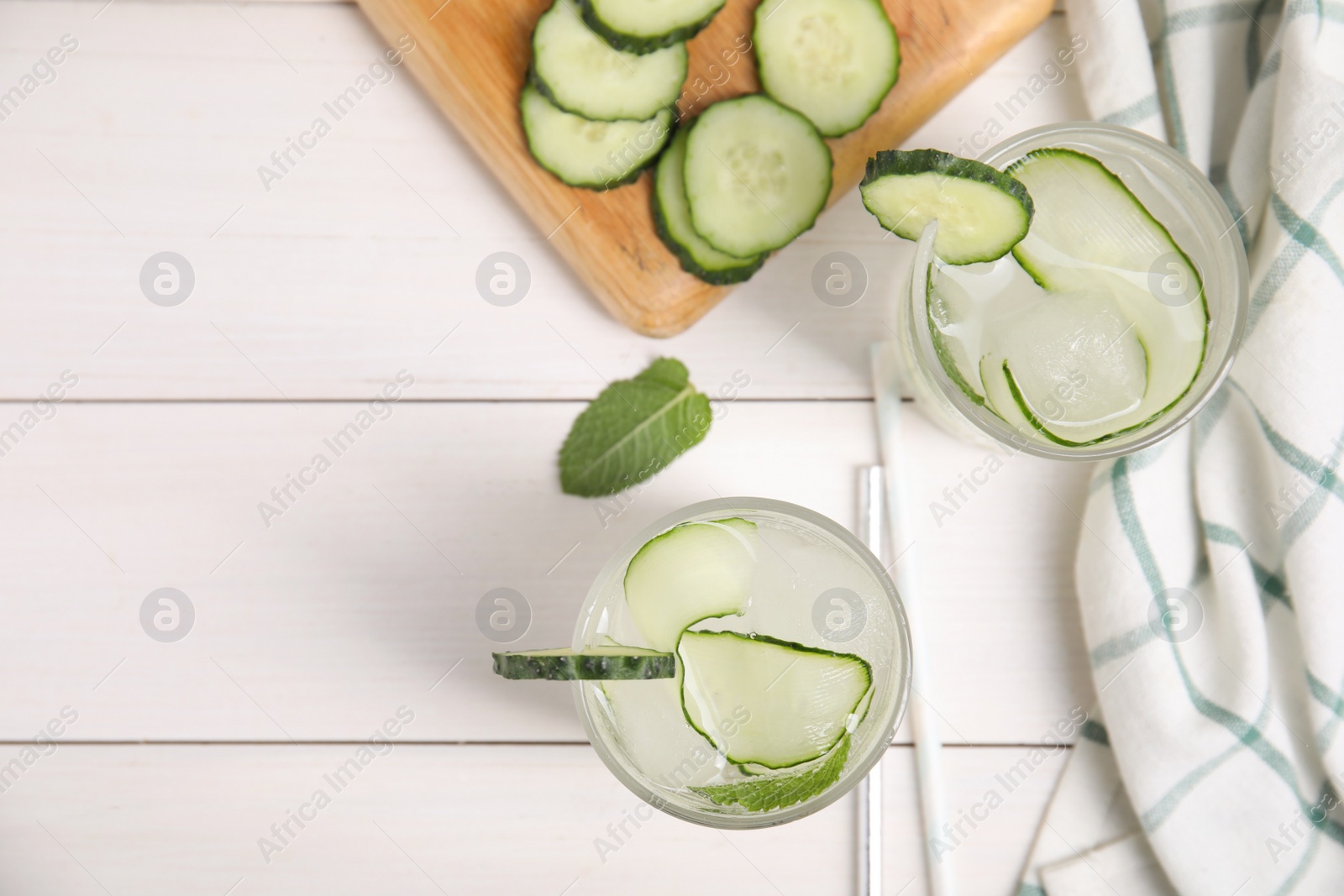 Photo of Tasty fresh cucumber water with mint on white wooden table, flat lay. Space for text