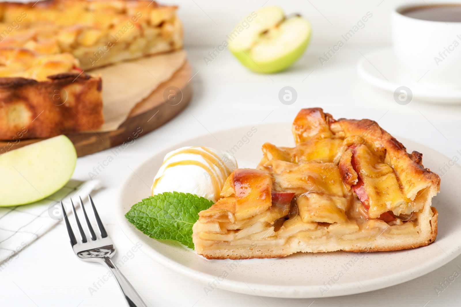 Photo of Slice of traditional apple pie with ice cream and mint on white table