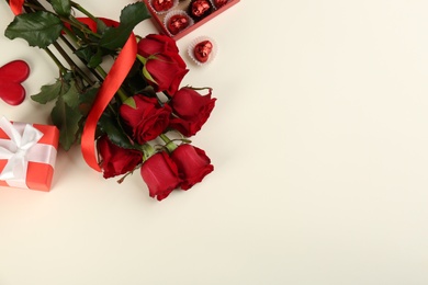 Photo of Flat lay composition with beautiful roses and gift box on light background, space for text. Valentine's Day celebration