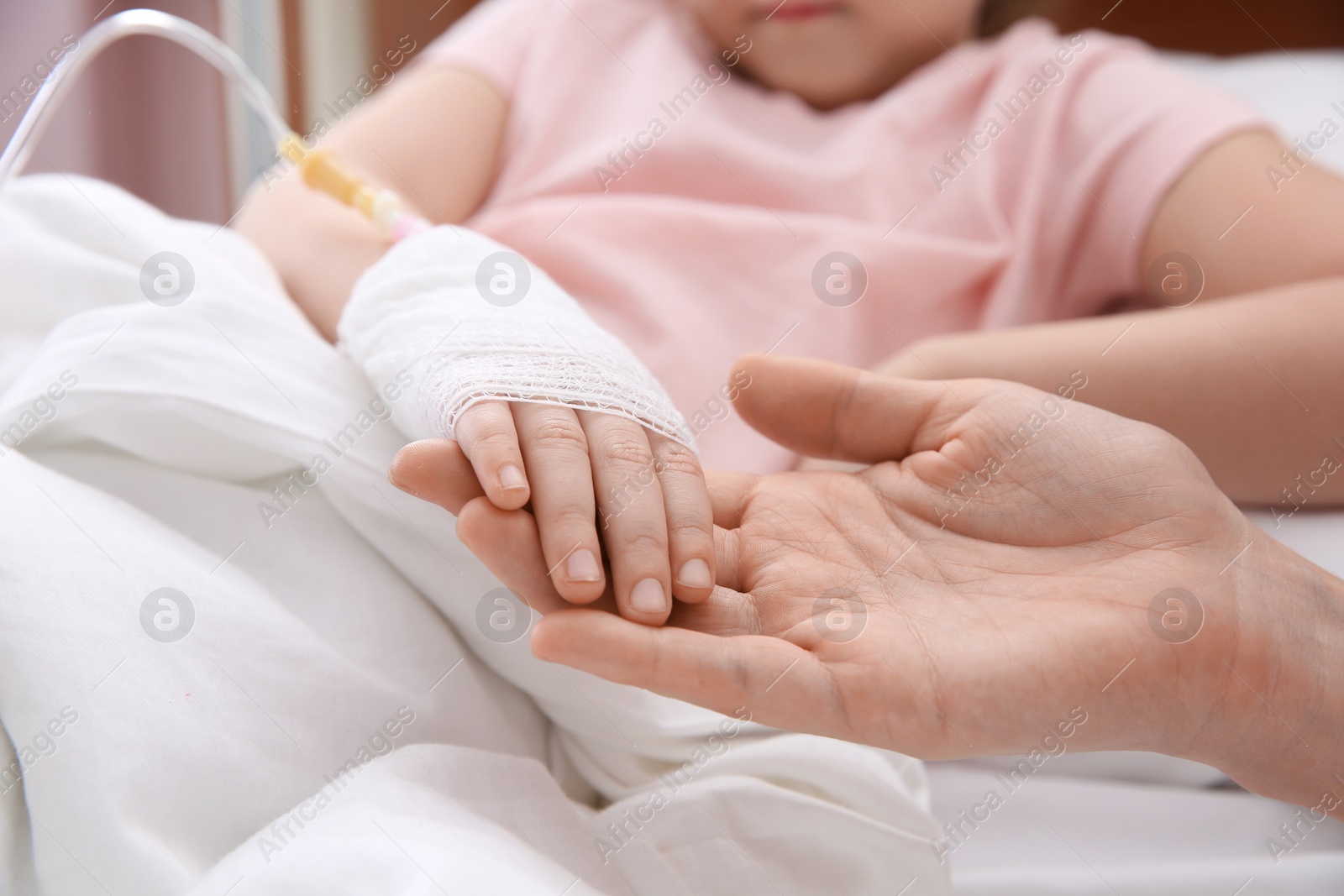 Photo of Doctor holding little child's hand with intravenous drip in hospital, closeup