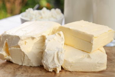 Photo of Tasty homemade butter and dairy products on wooden board outdoors, closeup