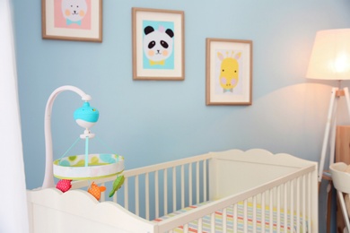 Photo of Cozy crib in light baby room interior