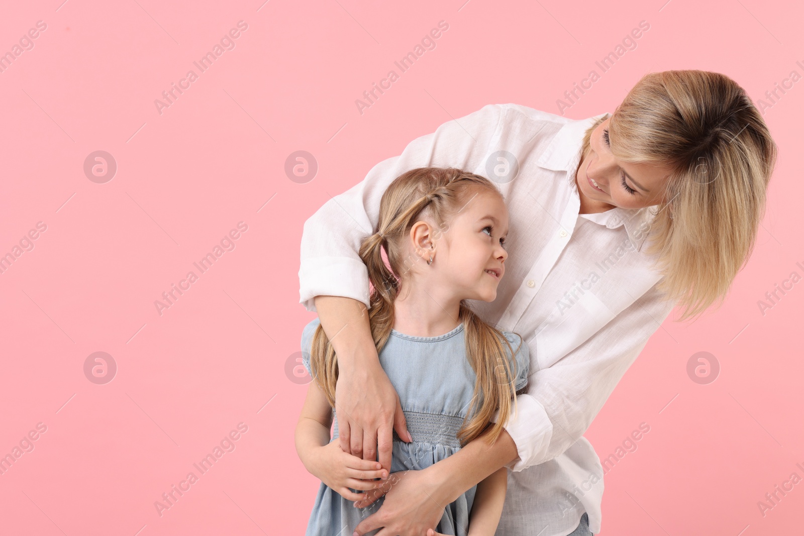 Photo of Family portrait of happy mother and daughter on pink background. Space for text