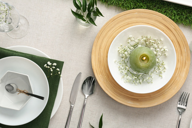 Elegant table setting with green plants on light cloth, flat lay