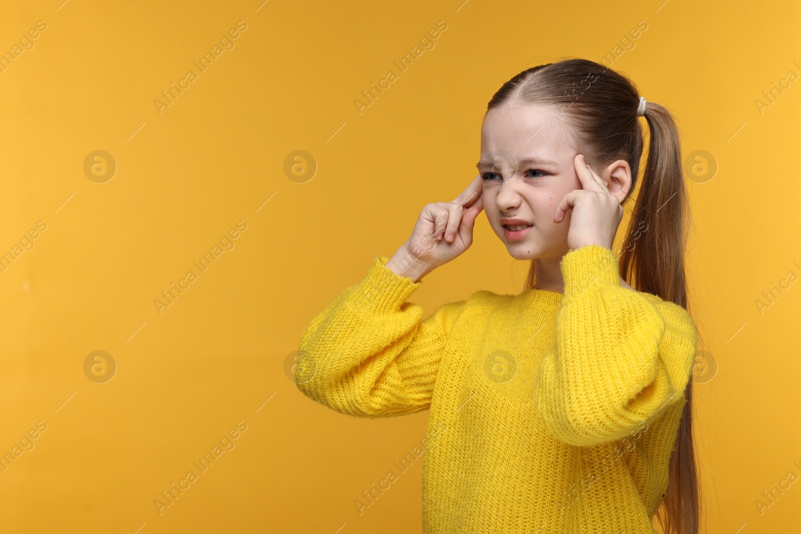 Photo of Little girl suffering from headache on yellow background. Space for text