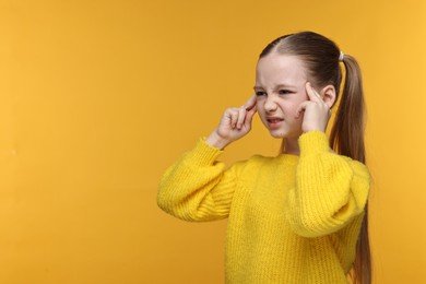 Photo of Little girl suffering from headache on yellow background. Space for text