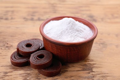 Photo of Bowl of fructose powder and fruit leather rolls on wooden table
