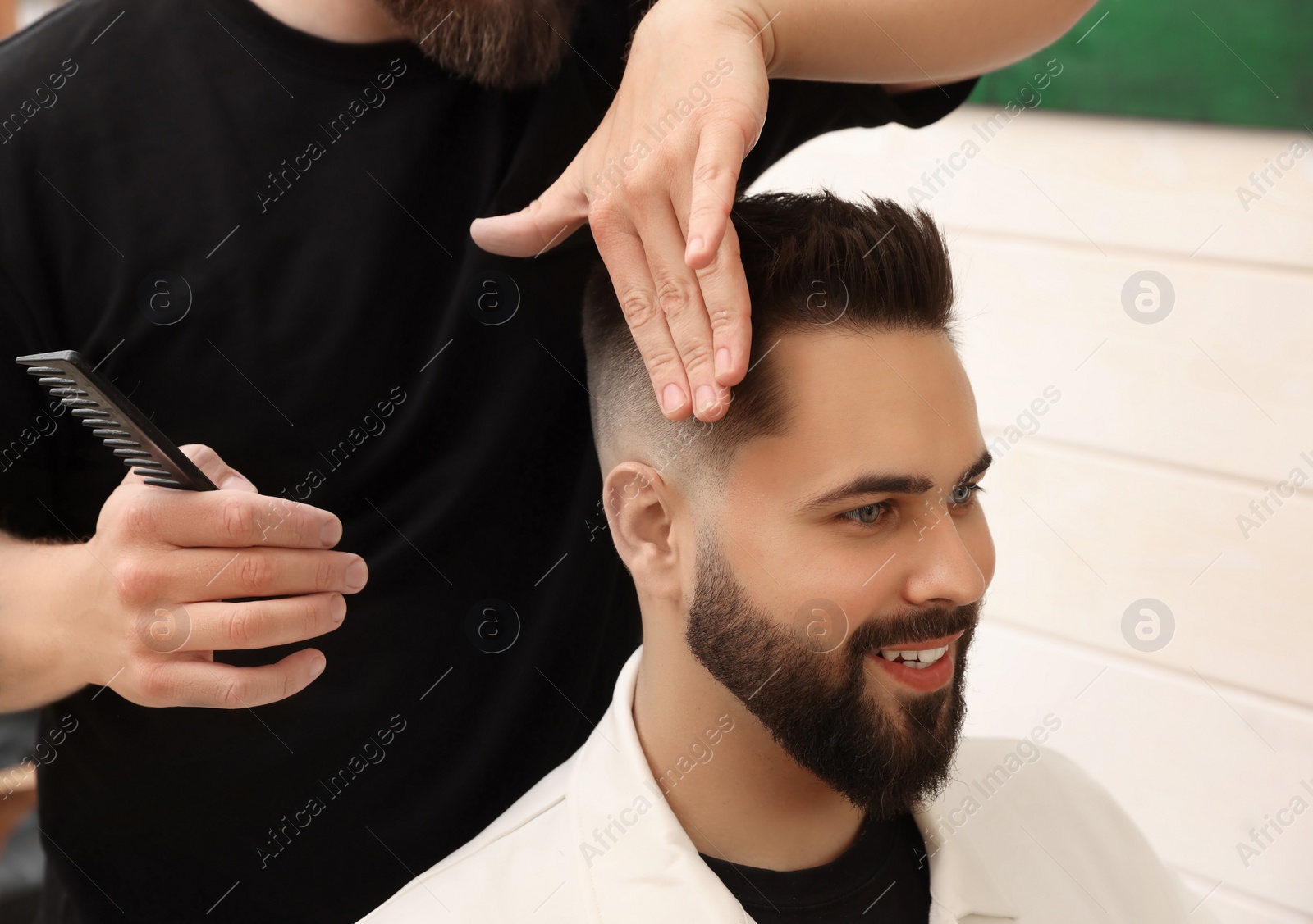 Photo of Professional hairdresser working with client in barbershop, closeup