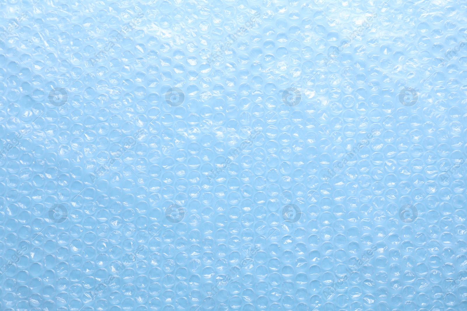 Photo of Transparent bubble wrap on light blue background, top view