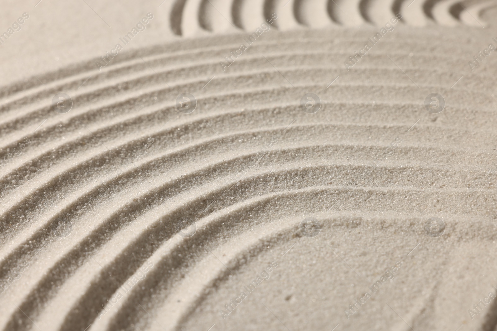 Photo of Beautiful lines drawn on sand, closeup. Zen garden