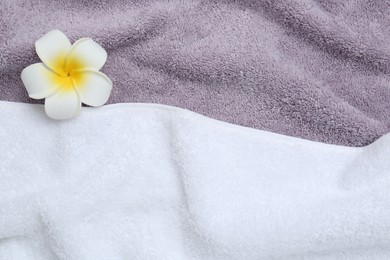 Photo of Plumeria flower on terry towels, top view. Space for text