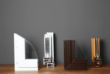 Samples of modern window profiles on table against gray wall. Installation service