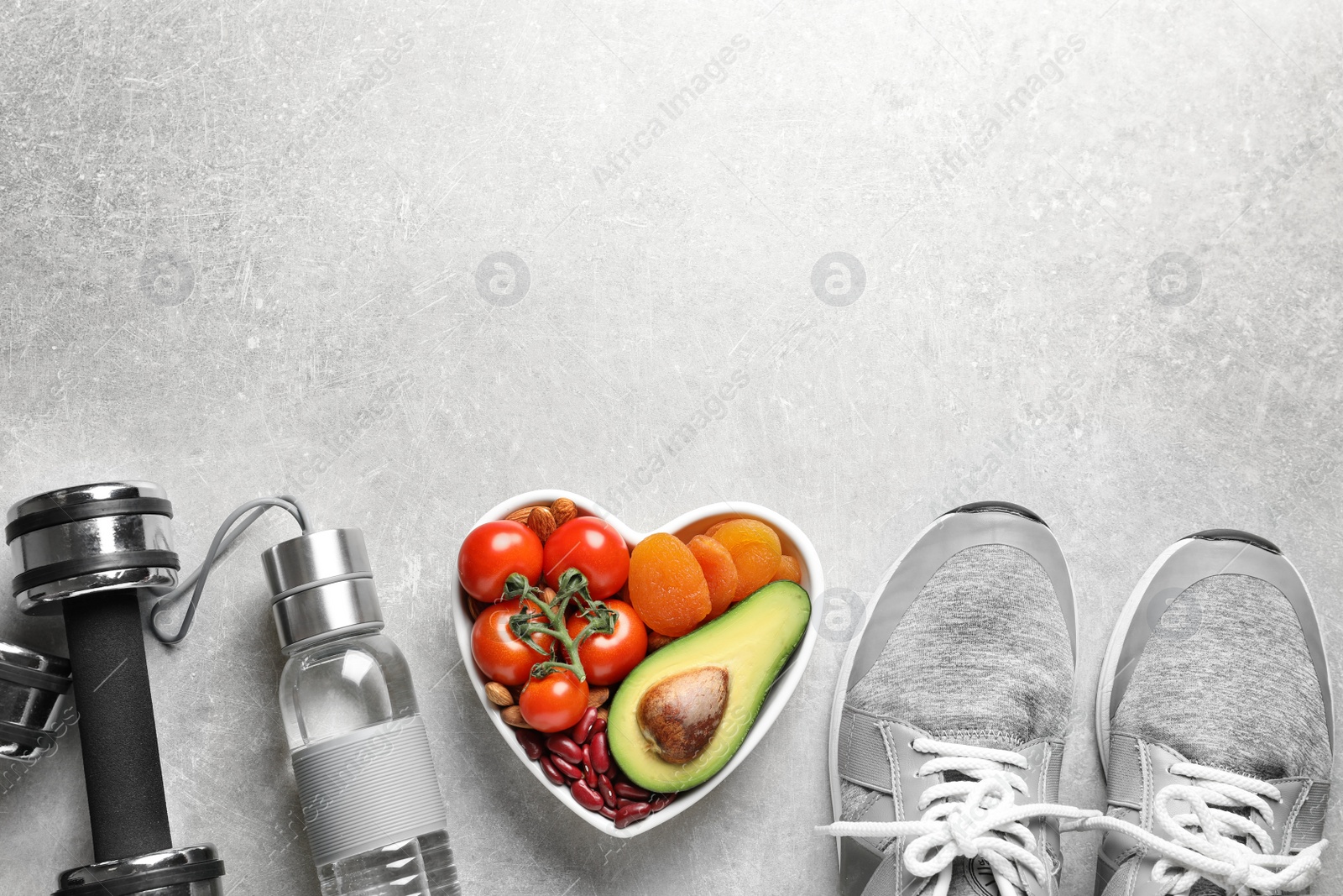 Photo of Heart-healthy products and sports equipment on grey background, flat lay. Space for text