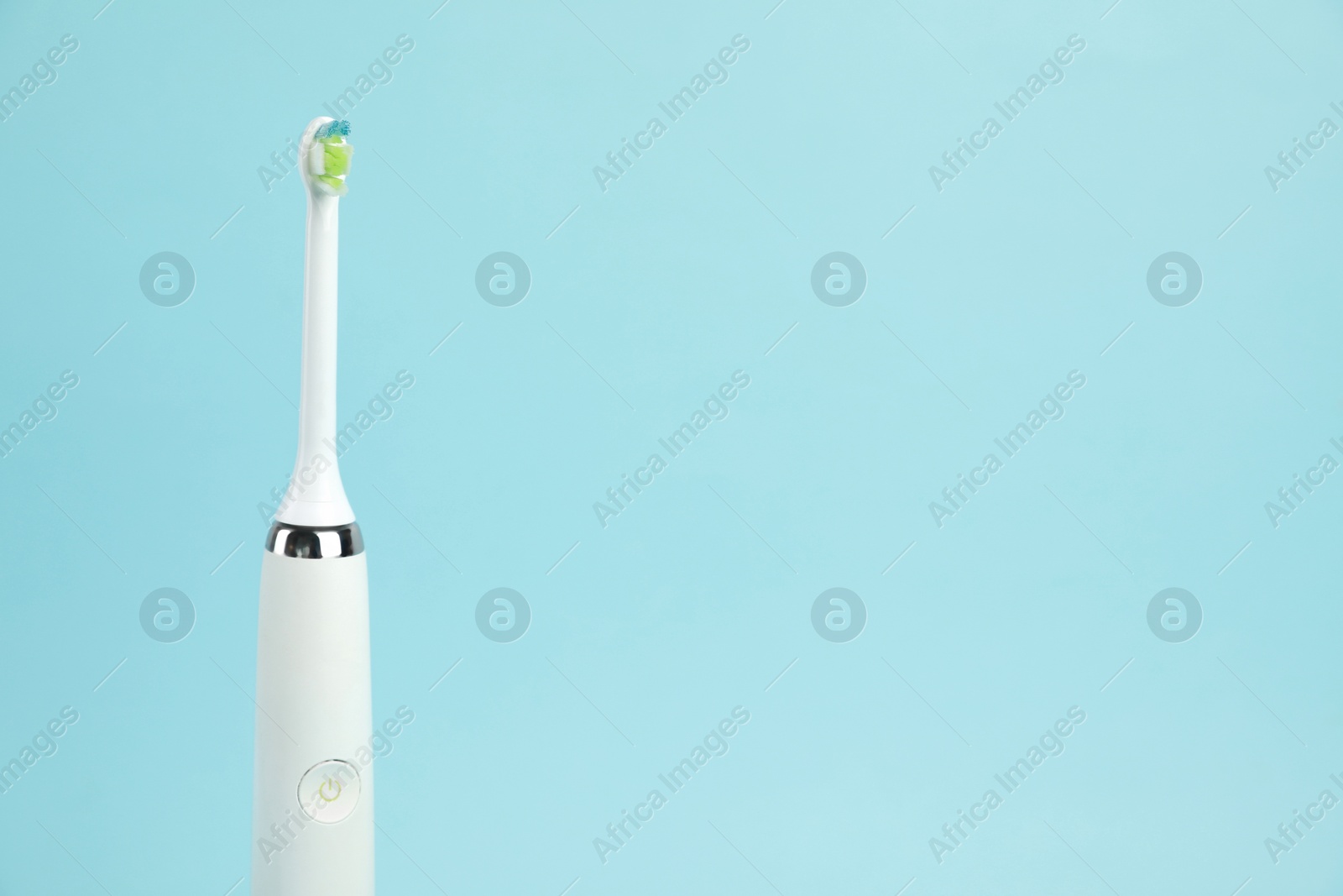 Photo of Electric toothbrush on light blue background, space for text