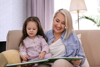 Photo of Granddaughter and grandmother reading book at home