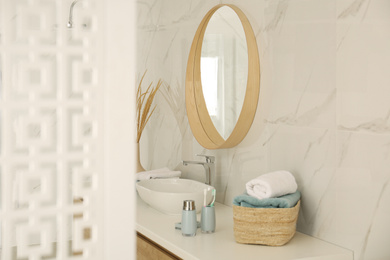 Round mirror over vessel sink in stylish bathroom interior