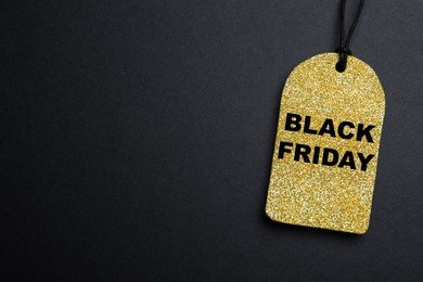 Photo of Golden tag with words Black Friday on dark background, top view. Space for text