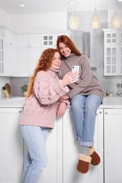 Photo of Beautiful young sisters spending time together in kitchen