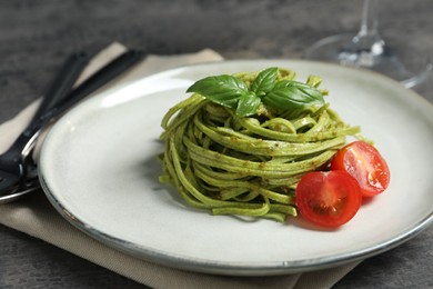 Photo of Tasty tagliatelle with spinach and tomatoes served on grey table, closeup. Exquisite presentation of pasta dish