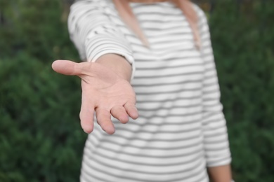 Woman offering helping hand outdoors, closeup view