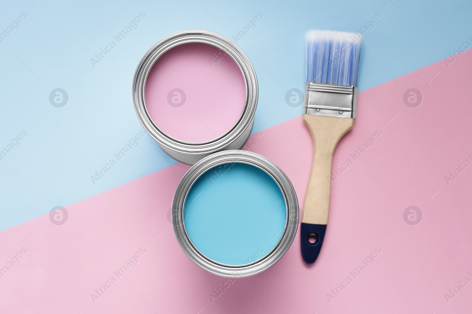 Photo of Cans with different paints and brush on color background, flat lay