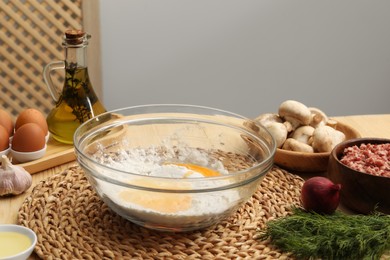 Bowl with flour, eggs and products on wooden table